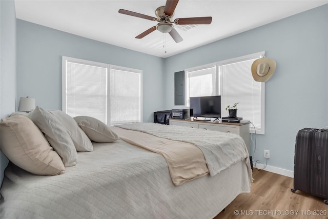 bedroom featuring a ceiling fan, light wood-type flooring, radiator, and baseboards