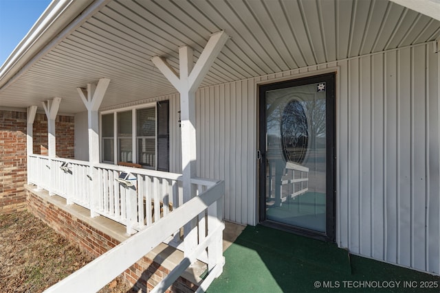 doorway to property with a porch and brick siding