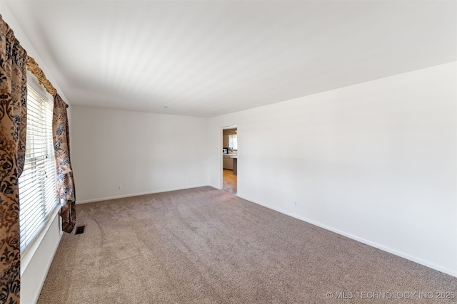 spare room with visible vents, baseboards, and light colored carpet