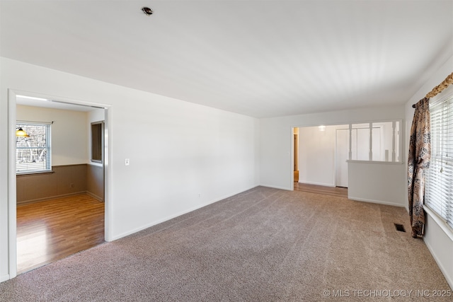 unfurnished room featuring wainscoting, carpet flooring, and visible vents