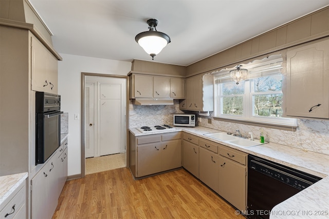 kitchen featuring light countertops, a sink, under cabinet range hood, and black appliances