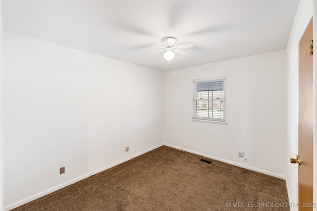 spare room with dark colored carpet, a ceiling fan, visible vents, and baseboards