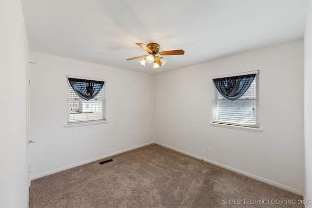 carpeted empty room featuring ceiling fan, visible vents, and baseboards