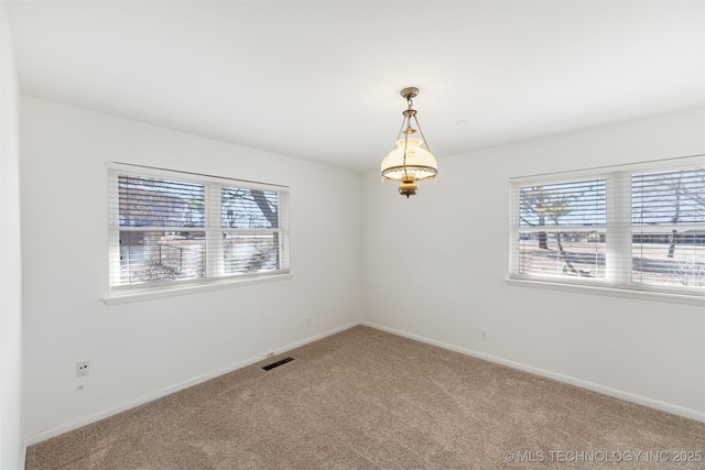 carpeted empty room featuring a healthy amount of sunlight, visible vents, and baseboards