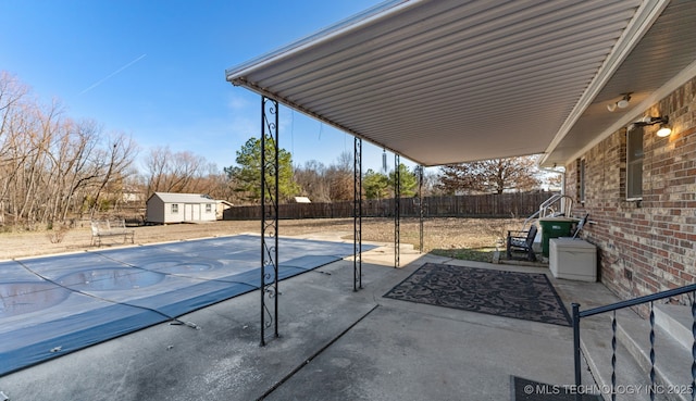 view of pool with an outbuilding, a patio area, a fenced backyard, and a storage unit