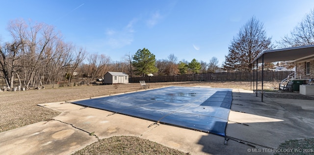 view of swimming pool featuring an outbuilding, a storage unit, a patio area, and a fenced backyard