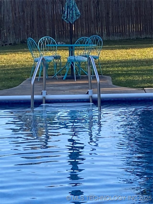 view of pool featuring a yard and fence