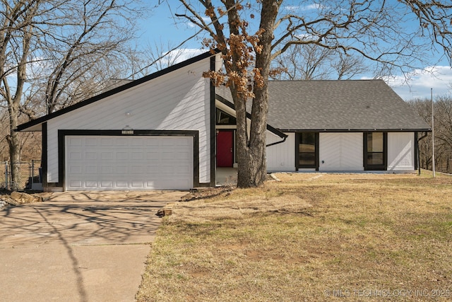 mid-century inspired home featuring a garage, a front yard, driveway, and a shingled roof