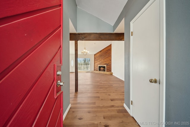 hallway with lofted ceiling with beams, light wood-type flooring, and a chandelier