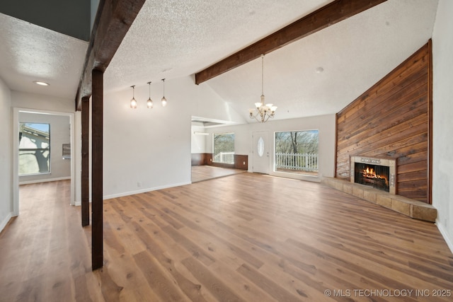 unfurnished living room with plenty of natural light, a textured ceiling, a tiled fireplace, and wood finished floors