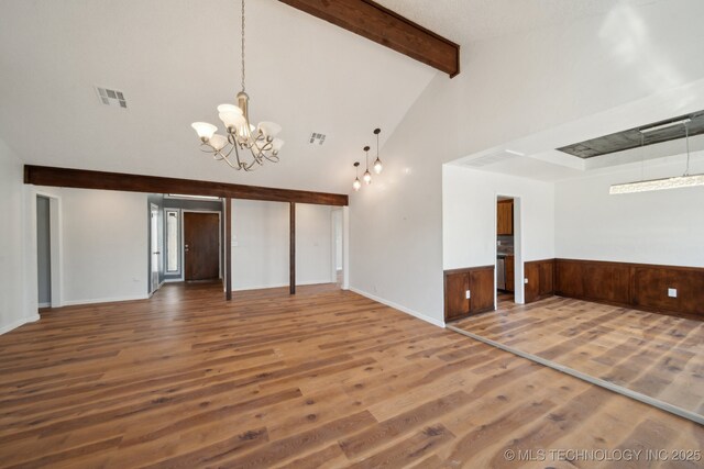 9435 S 33rd W Ave, Tulsa, OK 74132 - unfurnished living room featuring a chandelier, wood finished floors, beamed ceiling, a wainscoted wall, and high vaulted ceiling