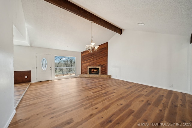 unfurnished living room featuring lofted ceiling with beams, a textured ceiling, a fireplace, and wood finished floors