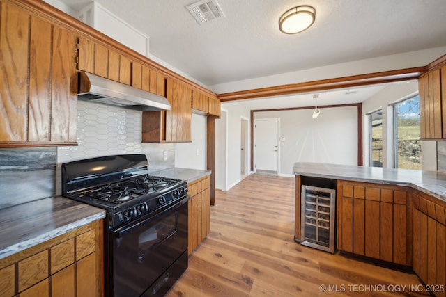 kitchen featuring visible vents, light wood-style floors, black range with gas cooktop, beverage cooler, and under cabinet range hood