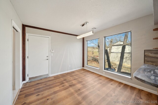 9435 S 33rd W Ave, Tulsa, OK 74132 - unfurnished dining area with wood finished floors, baseboards, and a textured ceiling