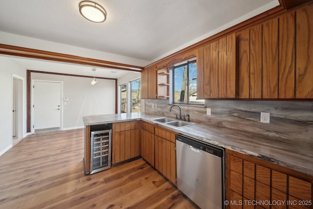 kitchen with brown cabinets, a sink, beverage cooler, dishwasher, and a peninsula