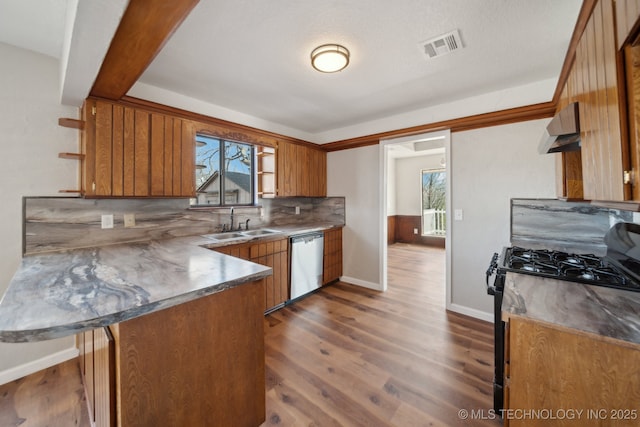 kitchen featuring dishwasher, a peninsula, black range with gas stovetop, extractor fan, and a sink