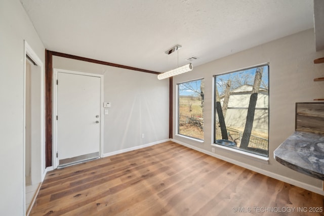 interior space with wood finished floors, visible vents, and baseboards