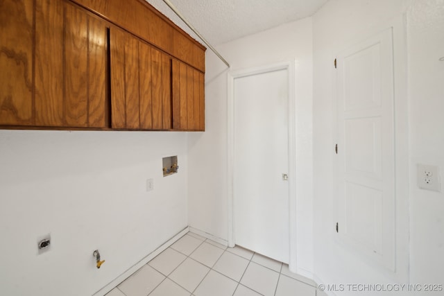 washroom with cabinet space, a textured ceiling, washer hookup, electric dryer hookup, and light tile patterned flooring