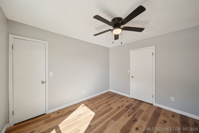 empty room featuring a textured ceiling, baseboards, and wood finished floors