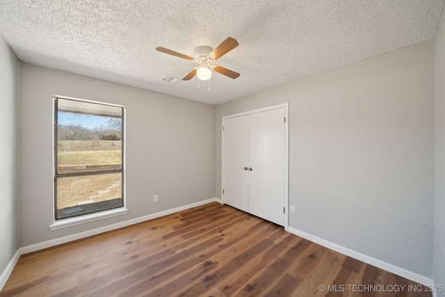 unfurnished bedroom with a closet, visible vents, baseboards, and wood finished floors