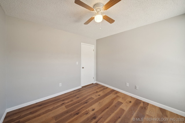 empty room with a textured ceiling, baseboards, and wood finished floors