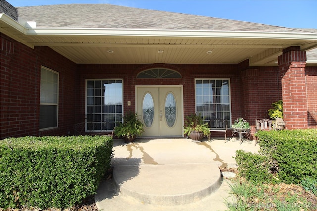 property entrance featuring a shingled roof and brick siding