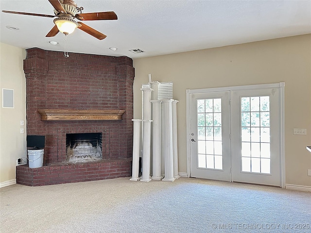 unfurnished living room with a brick fireplace, carpet, visible vents, and baseboards