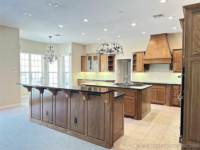 kitchen featuring a kitchen island with sink, a breakfast bar, a sink, open shelves, and custom range hood