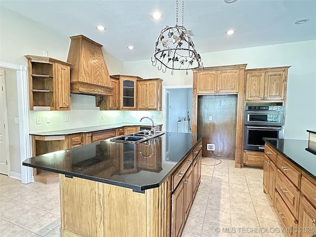 kitchen featuring open shelves, double oven, a kitchen island with sink, a sink, and premium range hood