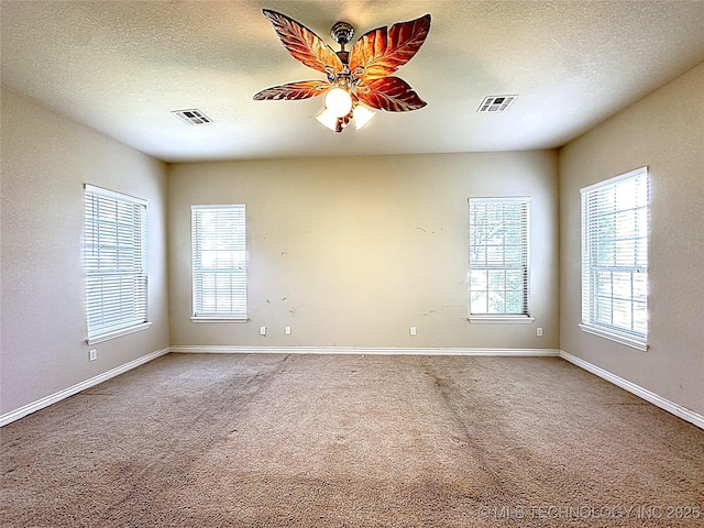 carpeted spare room with visible vents, ceiling fan, and a textured ceiling