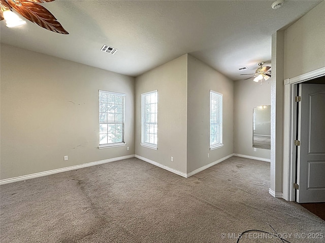 carpeted empty room featuring ceiling fan, a textured ceiling, visible vents, and baseboards