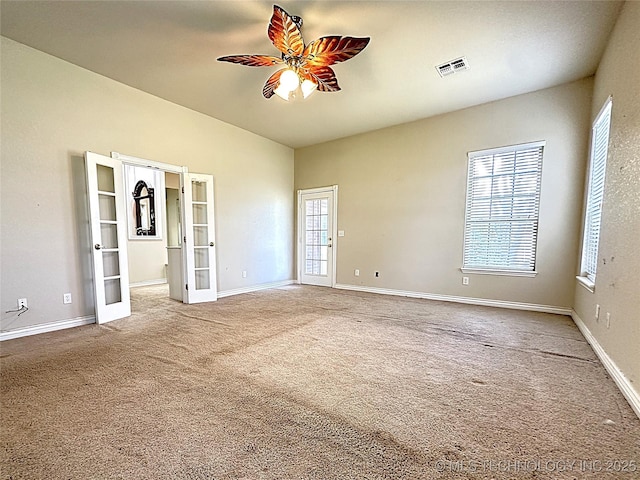 carpeted empty room with ceiling fan, french doors, visible vents, and baseboards