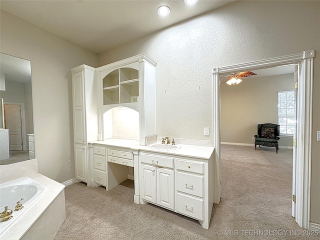 full bath with carpet floors, vanity, a bath, and baseboards