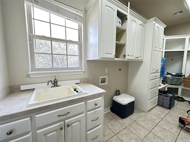 washroom featuring hookup for an electric dryer, washer hookup, a sink, visible vents, and cabinet space