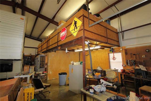 garage with refrigerator, a workshop area, and wooden walls