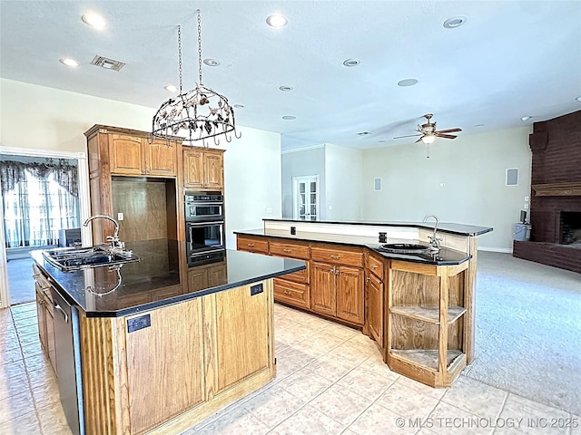 kitchen featuring visible vents, a sink, a center island with sink, and dobule oven black