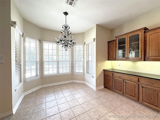 unfurnished dining area with baseboards, visible vents, a notable chandelier, and light tile patterned flooring