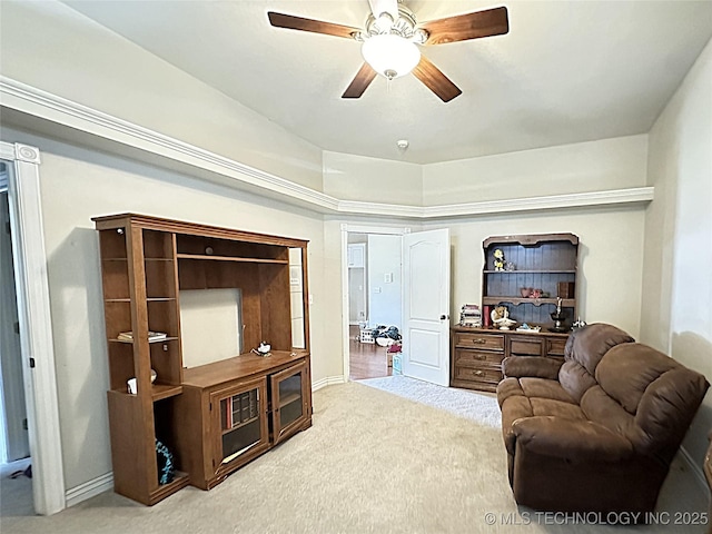 living area featuring ceiling fan, baseboards, and carpet flooring