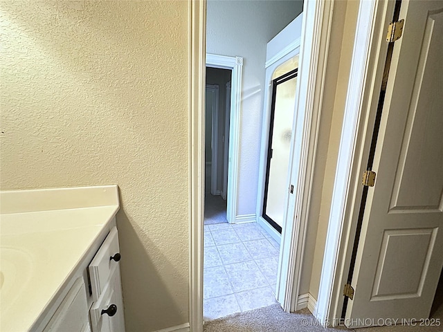 bathroom featuring tile patterned flooring, a textured wall, vanity, and a shower stall