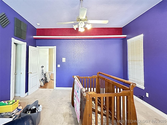 carpeted bedroom featuring ceiling fan, a crib, visible vents, and baseboards