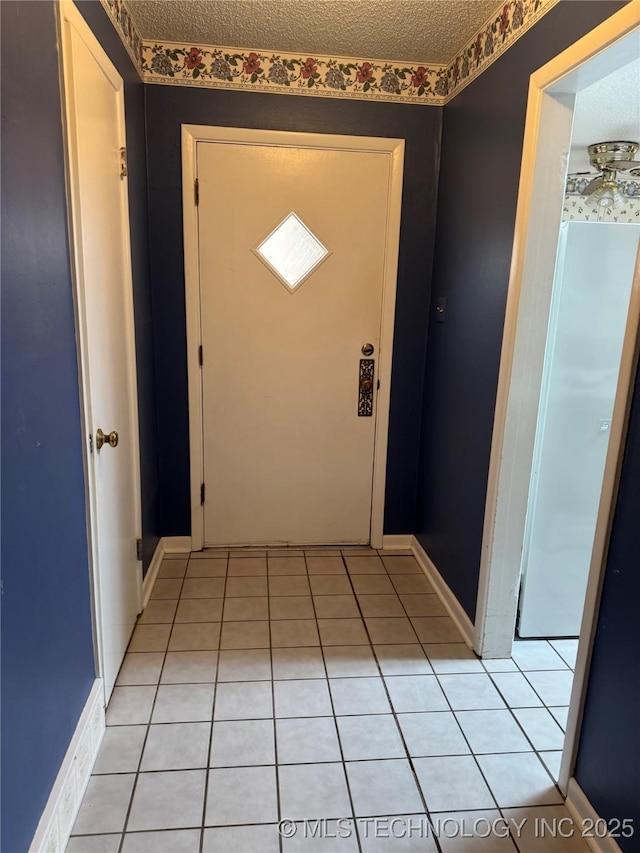 doorway with light tile patterned floors, baseboards, and a textured ceiling