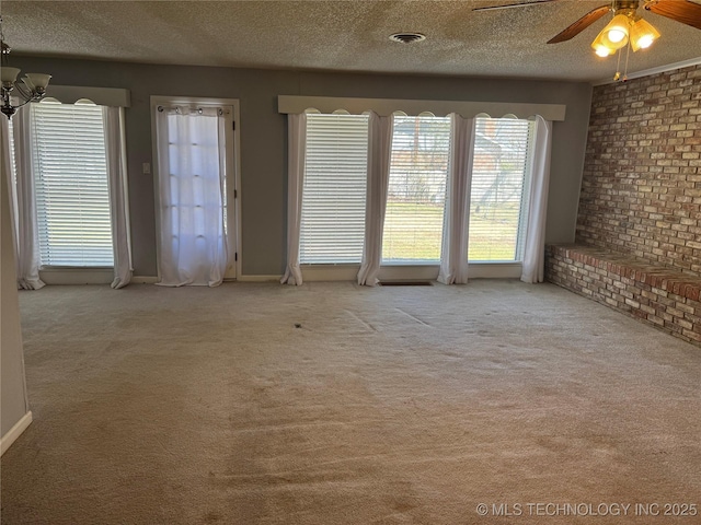 unfurnished living room featuring carpet, visible vents, ceiling fan, and a textured ceiling