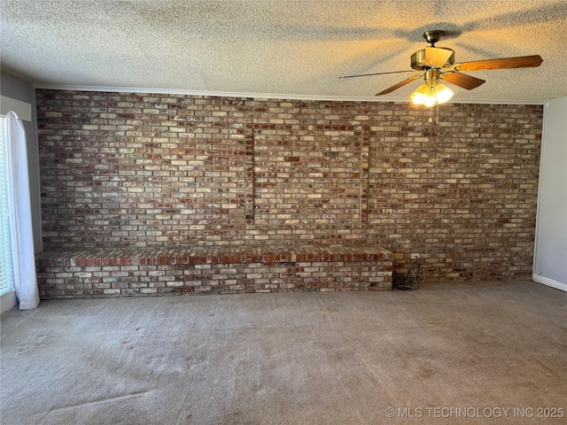 unfurnished living room featuring a textured ceiling, carpet floors, ceiling fan, and brick wall