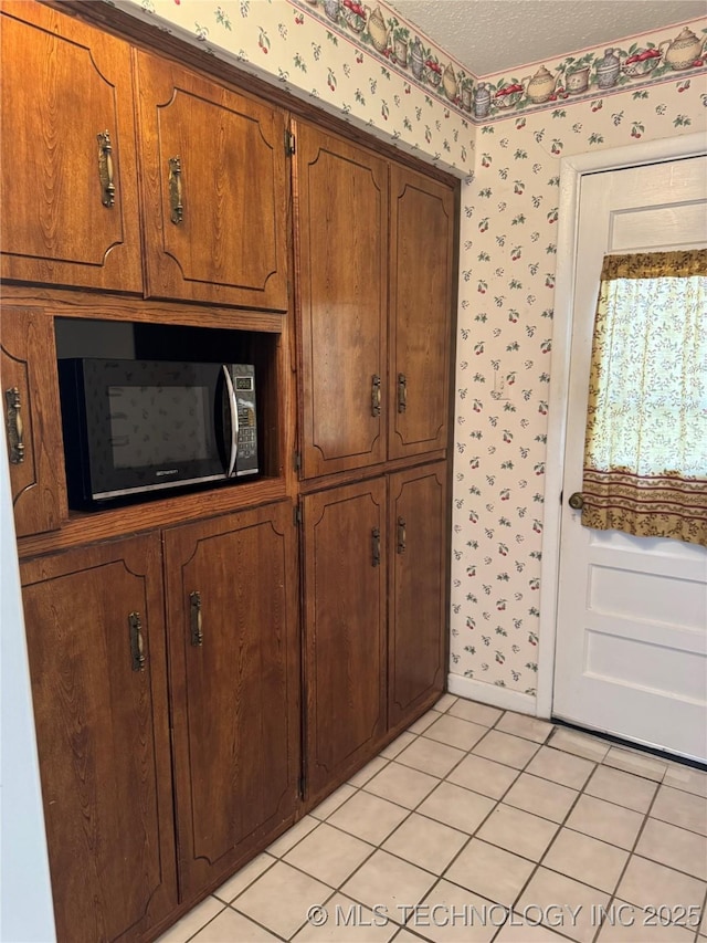 interior space featuring black microwave, a textured ceiling, and wallpapered walls