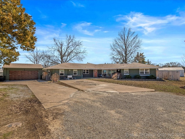 single story home with driveway, an attached garage, an outdoor structure, and fence