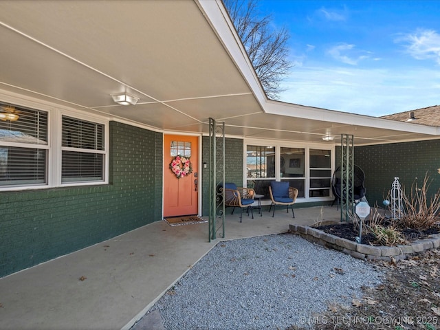 entrance to property featuring brick siding and a patio