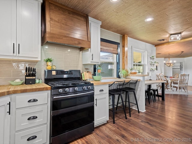 kitchen with dark wood-style flooring, range with two ovens, custom range hood, and wooden counters