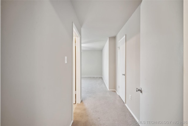 hallway with light colored carpet and baseboards
