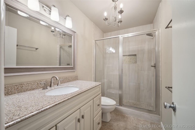bathroom featuring tile patterned flooring, toilet, a stall shower, an inviting chandelier, and vanity