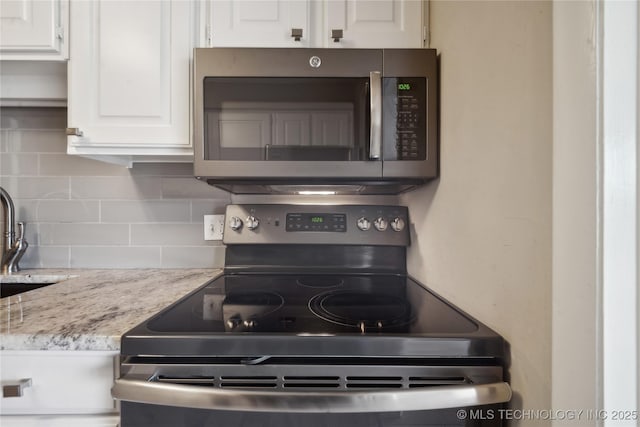 kitchen featuring stainless steel appliances, white cabinets, and decorative backsplash